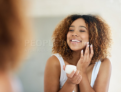 Buy stock photo Shot of a young woman applying moisturizer to her face