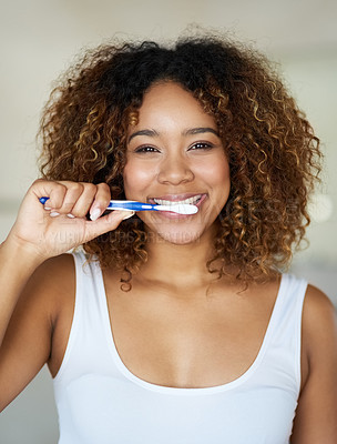 Buy stock photo Shot of a young woman brushing her teeth in her bathroom