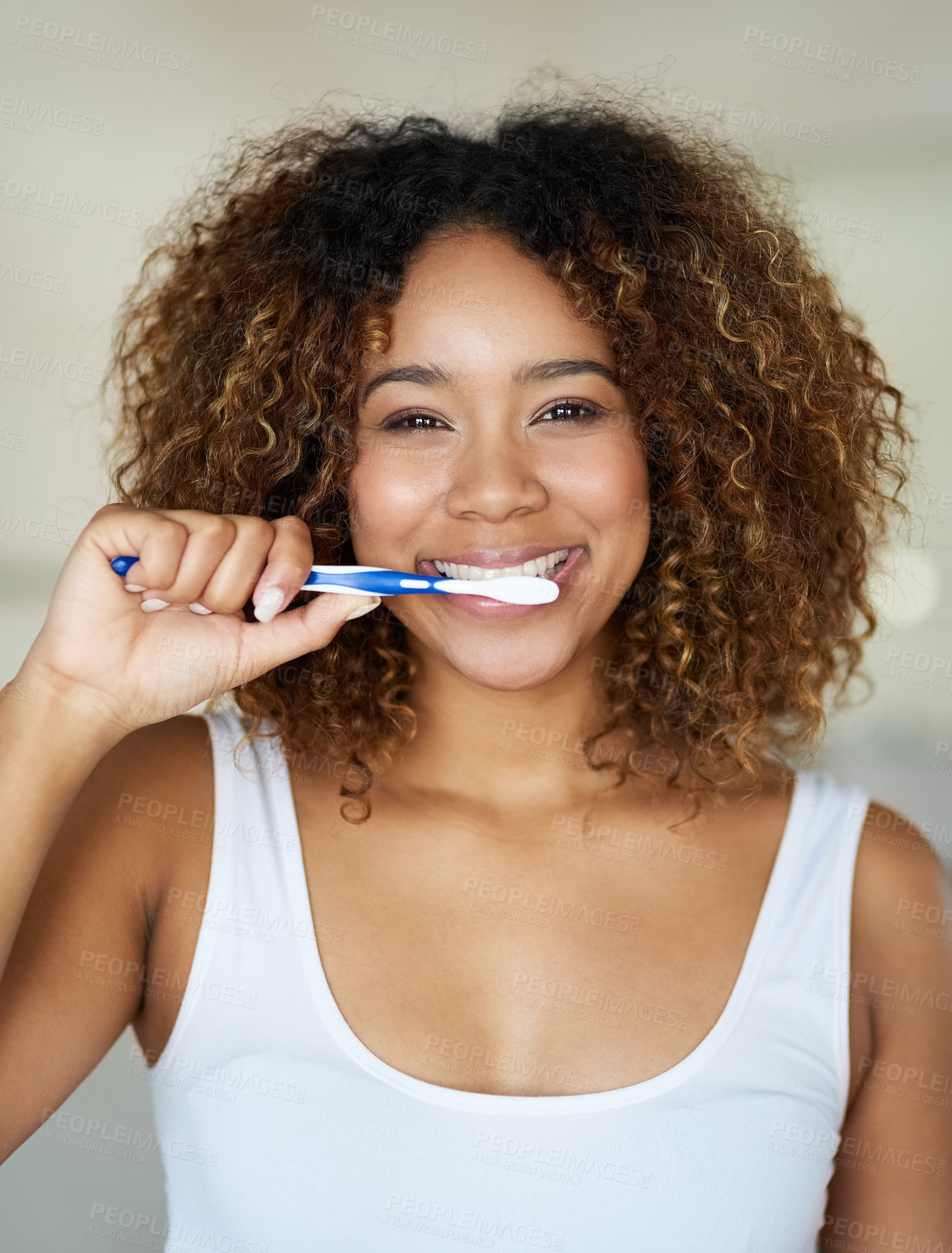 Buy stock photo Shot of a young woman brushing her teeth in her bathroom