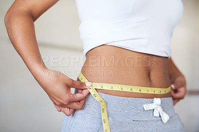 Buy stock photo Cropped shot of a young woman measuring her waist in the bathroom