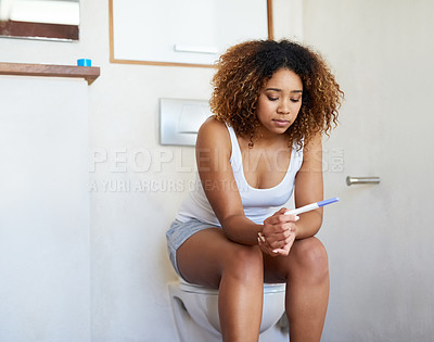 Buy stock photo Shot of a young woman looking at the results on her pregnancy test