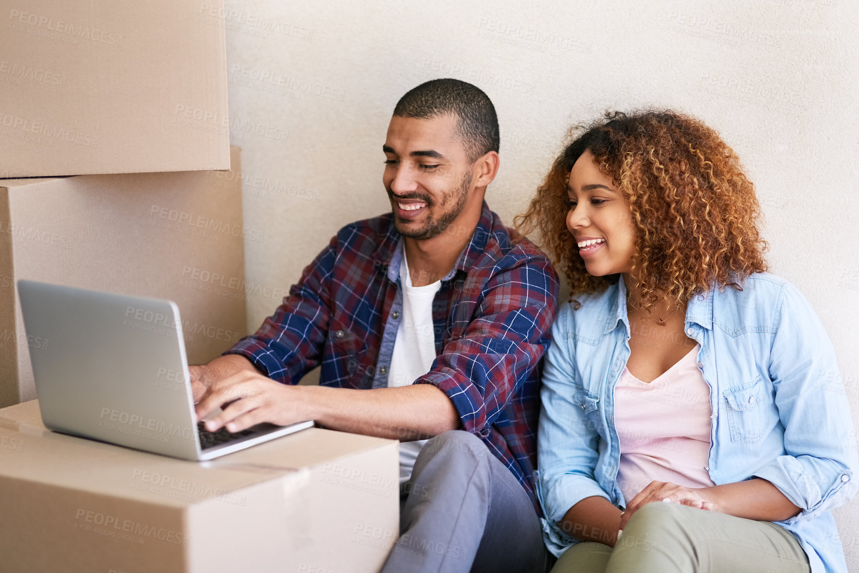 Buy stock photo Shot of a young couple using a laptop while sitting among boxes on moving day