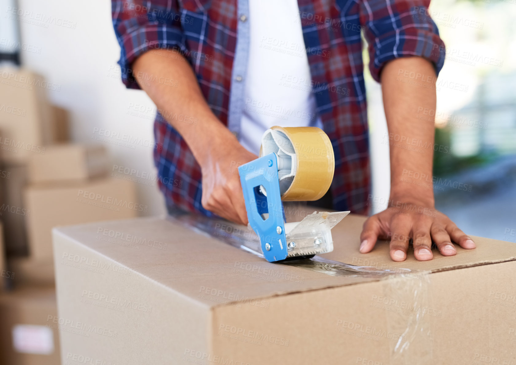 Buy stock photo Shot of an unidentifiable man using a tape dispenser to close a box while moving house