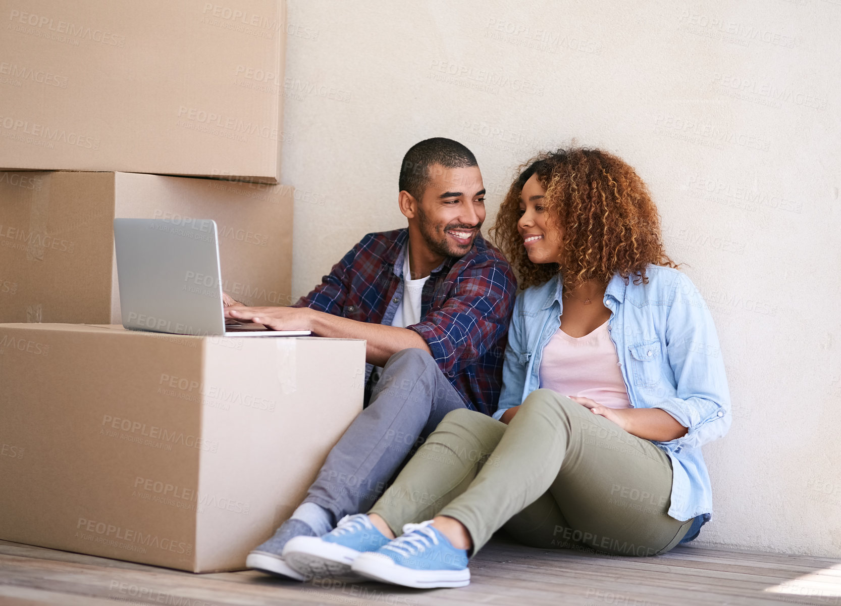 Buy stock photo Shot of a young couple using a laptop while sitting among boxes on moving day