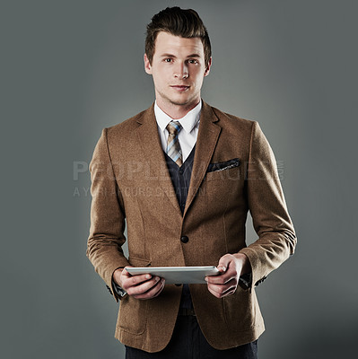 Buy stock photo Studio shot of a young businessman using his tablet against a grey background