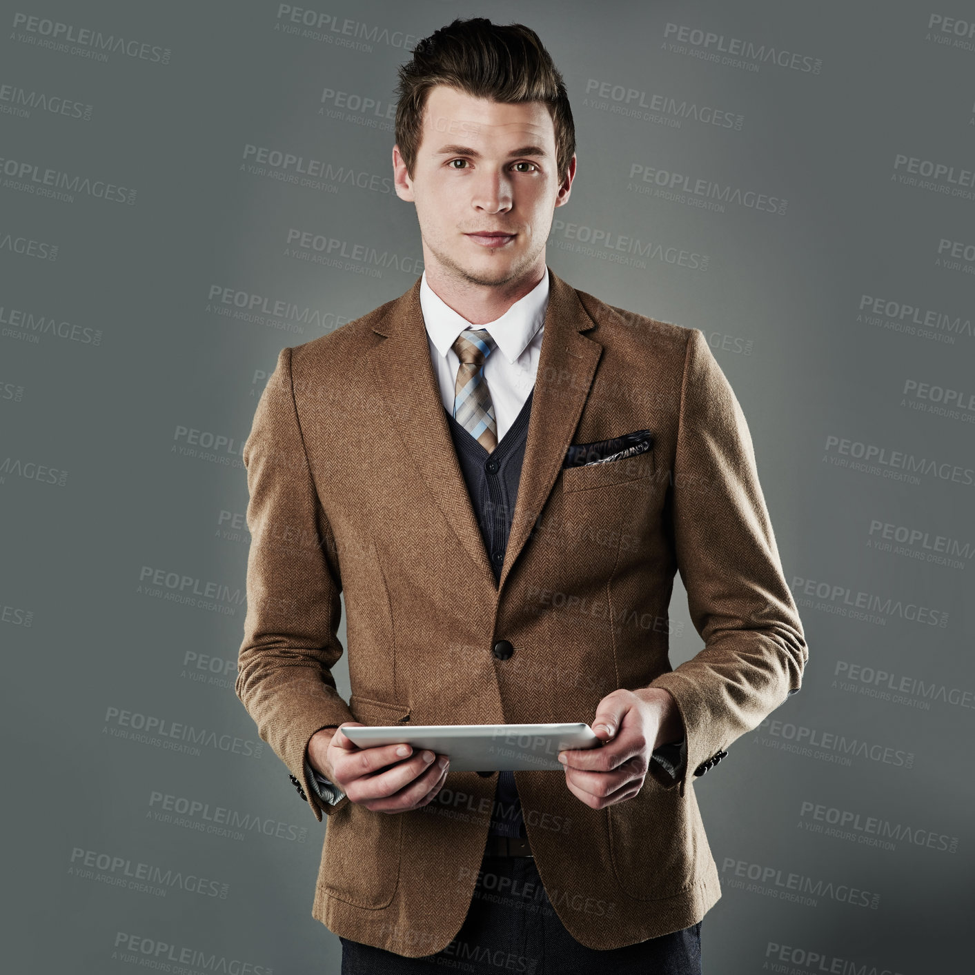 Buy stock photo Studio shot of a young businessman using his tablet against a grey background