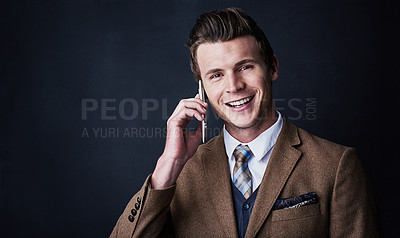 Buy stock photo Studio shot of a young businessman using his cellphone against a dark background