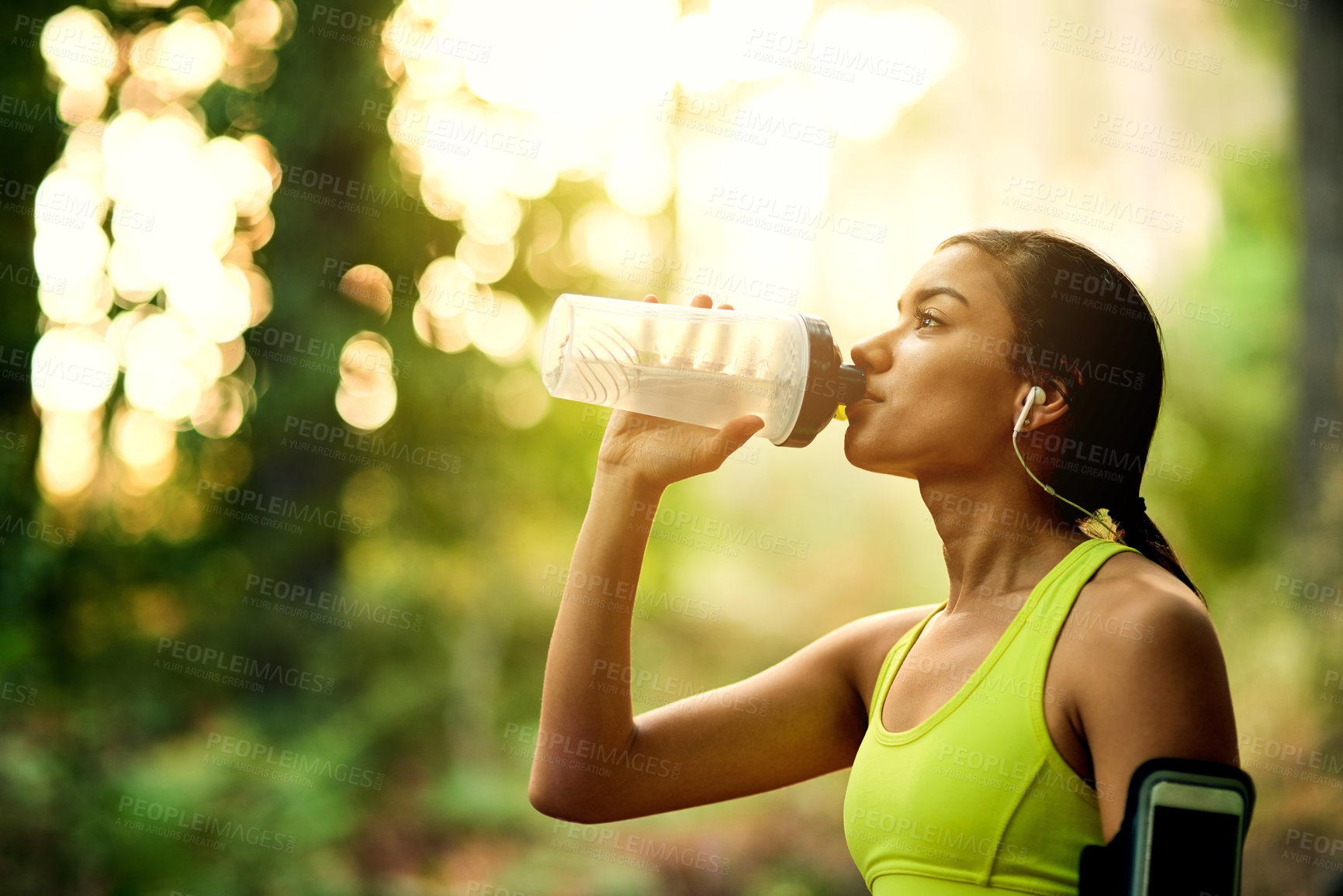 Buy stock photo Running, fitness and girl drinking water in park with earphones for wellness, workout and training in nature with radio. Sports, liquid or thirsty runner with refreshing beverage in forest for cardio