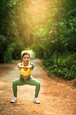 Buy stock photo Shot of a sporty young woman dong squats in a natural environment