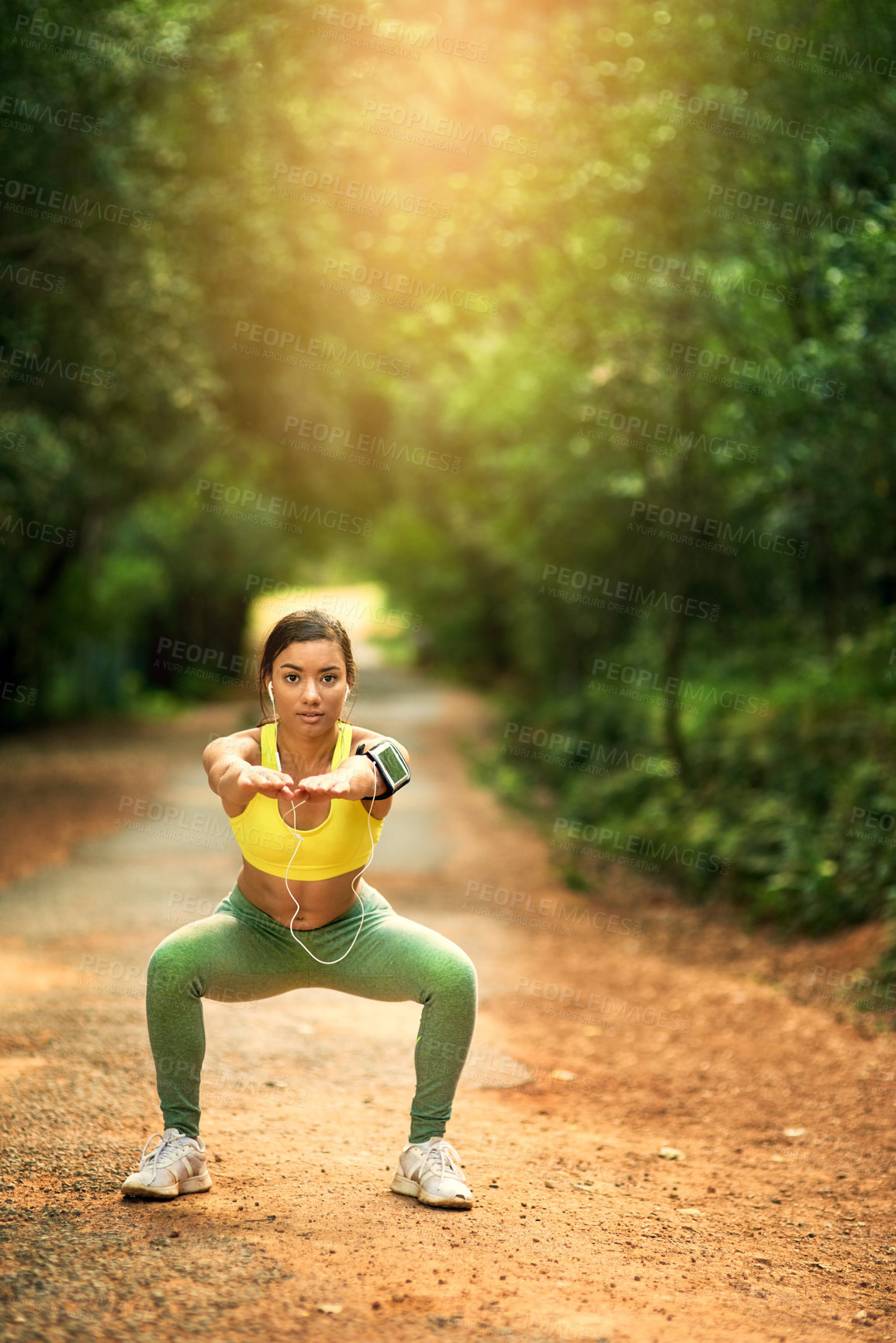 Buy stock photo Shot of a sporty young woman dong squats in a natural environment