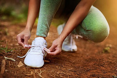 Buy stock photo Shot of a sporty young woman tying her shoelaces before a run