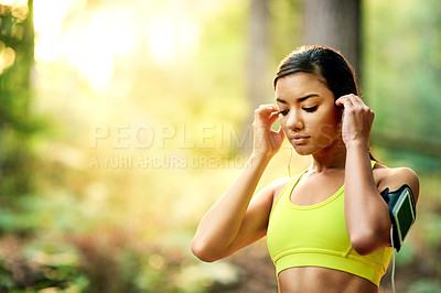 Buy stock photo Shot of a young woman putting in her earphones before her run