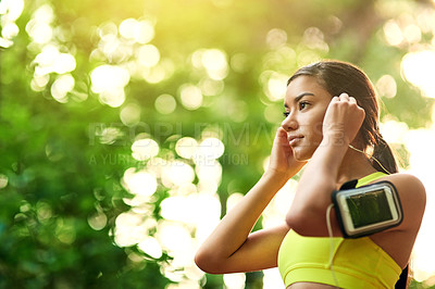 Buy stock photo Shot of a young woman putting in her earphones before her run