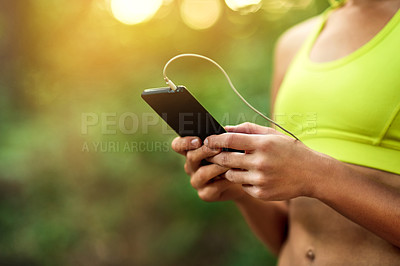 Buy stock photo Cropped shot of a young woman using her phone while out for a run