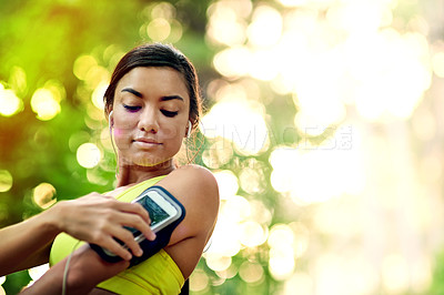Buy stock photo Shot of a young woman selecting a playlist before her run