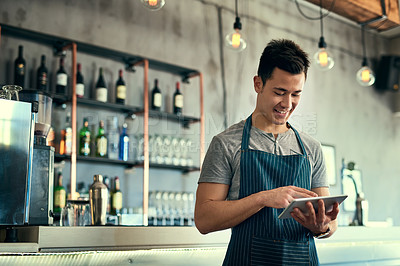 Buy stock photo Cropped shot of a young man working on a tablet in his coffee shop