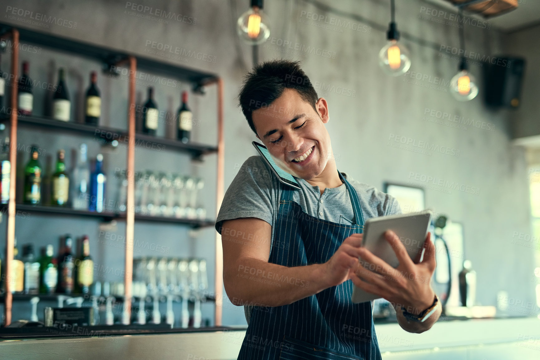Buy stock photo Shot of a young man taking orders via cellphone and logging them on his tablet
