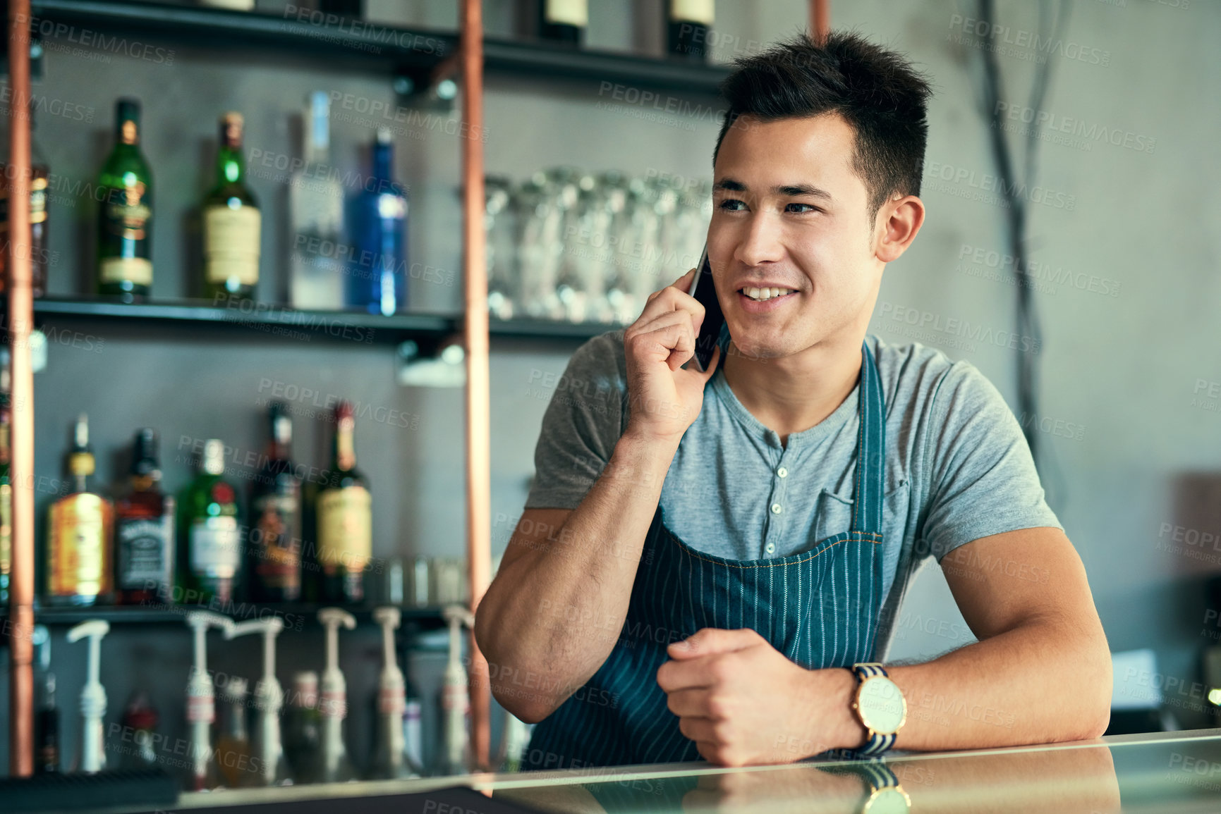 Buy stock photo Cropped shot of a young man taking orders via cellphone in his coffee shop
