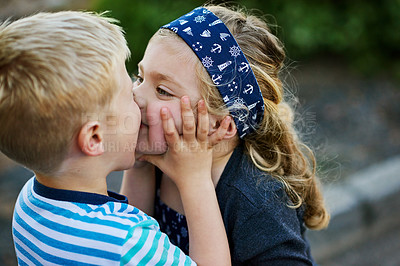 Buy stock photo Shot of a little girl giving her brother a kiss while they play together outside