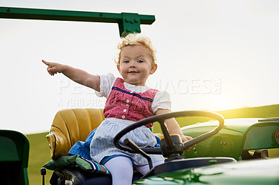 Buy stock photo Portrait of an adorable little girl riding a tractor on a farm
