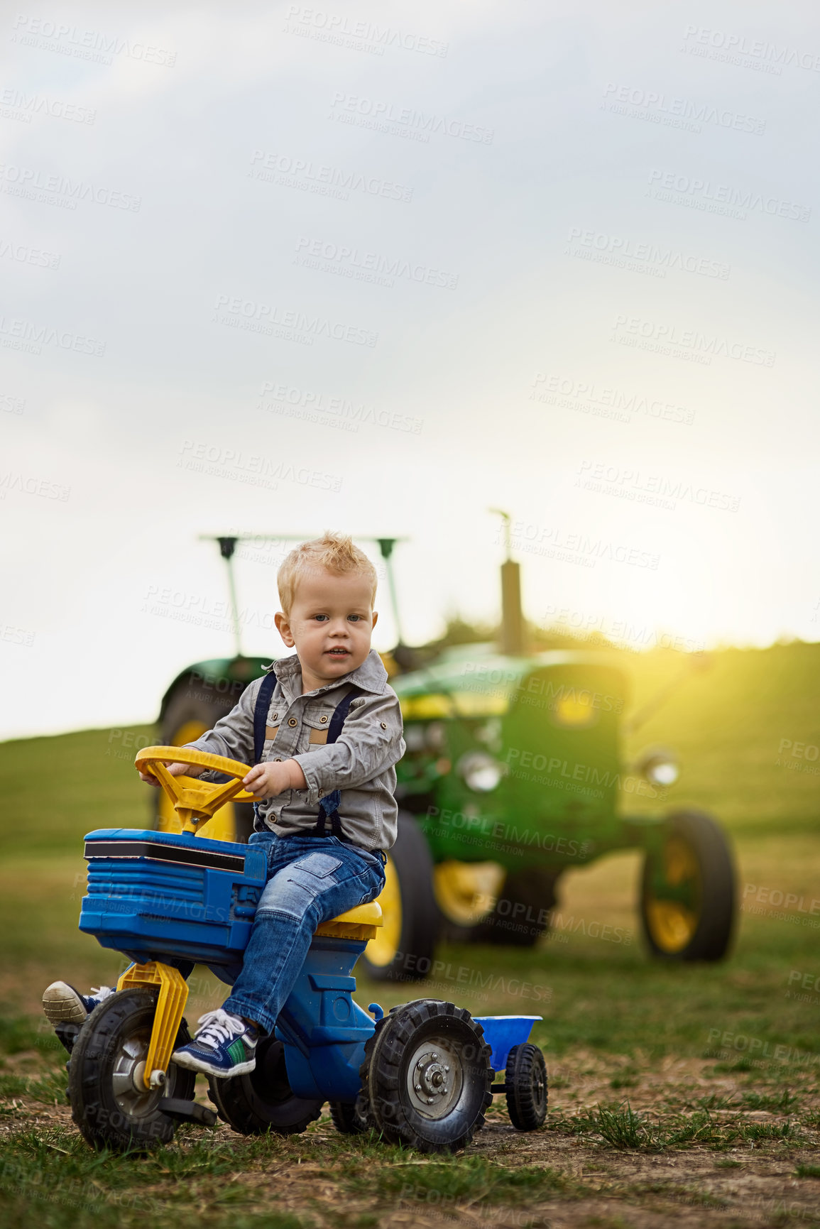Buy stock photo Portrait of an adorable little boy riding a toy truck on a farm