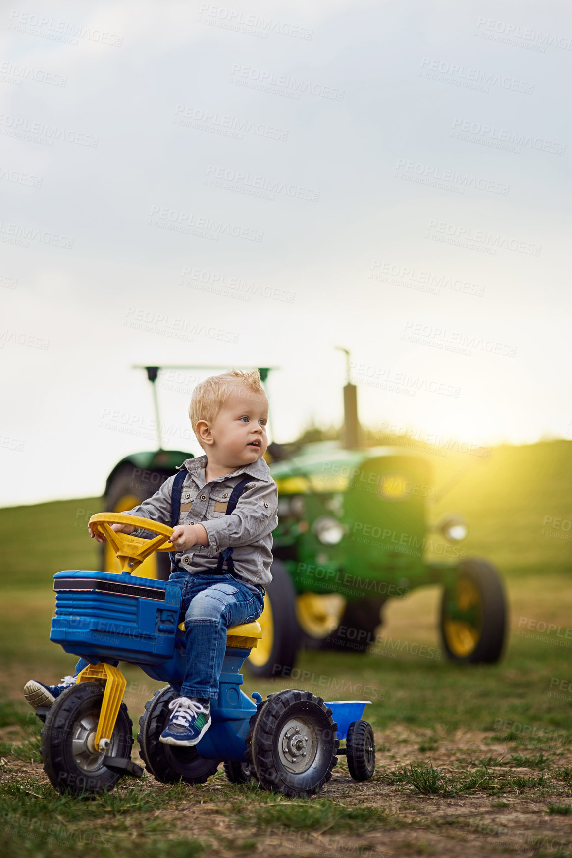 Buy stock photo Shot of an adorable little boy riding a toy truck on a farm