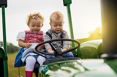 Buy stock photo Shot of two adorable children riding a tractor together on a farm