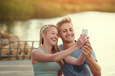 Buy stock photo Cropped shot of a young couple taking a selfie together outside