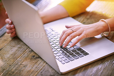 Buy stock photo Cropped shot of an unrecognizable woman using her laptop outside