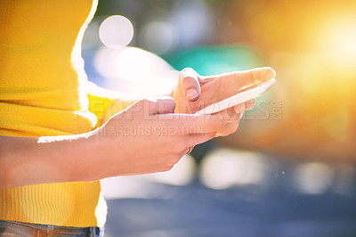 Buy stock photo Cropped shot of an unrecognizable young woman using a smartphone outside