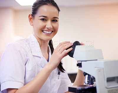 Buy stock photo Portrait of a young scientist using a microscope in a laboratory