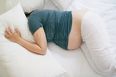 Buy stock photo Shot of a pregnant woman lying with her head under her pillow