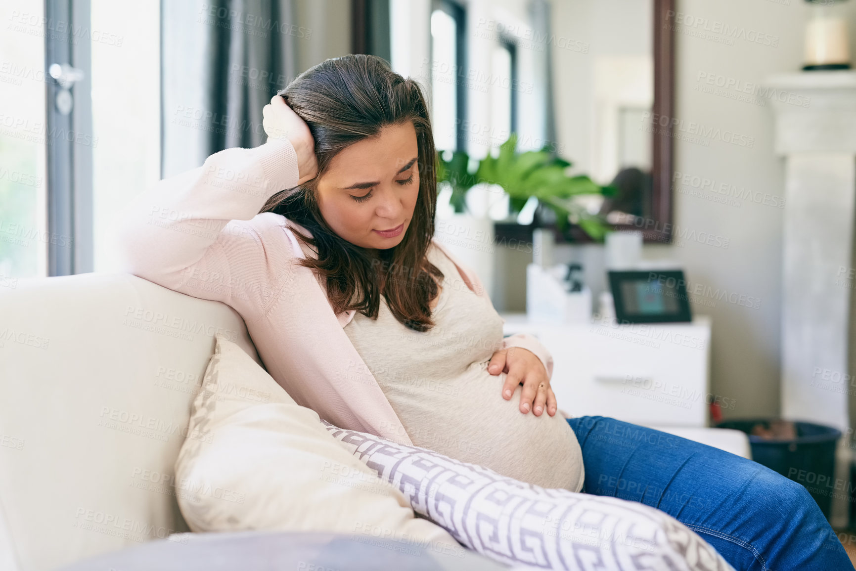 Buy stock photo Pregnancy, woman and tired on sofa in home, physical and emotional change for motherhood. Pregnant girl, sleeping and resting on couch for wellness, health and massage belly with hand for comfort