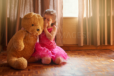 Buy stock photo Shot of a little girl whispering something in her teddy bear's ear