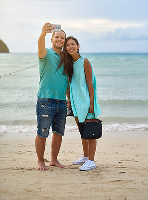 Buy stock photo Shot of a couple taking a selfie on the beach