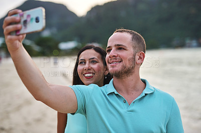 Buy stock photo Shot of a couple taking a selfie on the beach