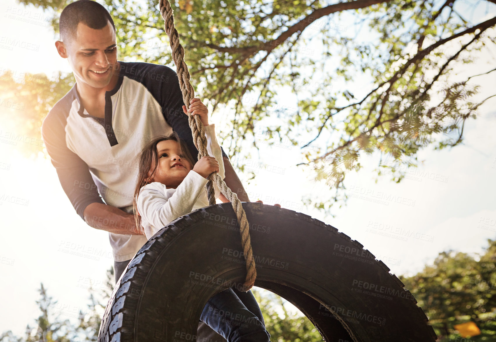 Buy stock photo Shot of a happy father pushing his daughter on a tyre swing