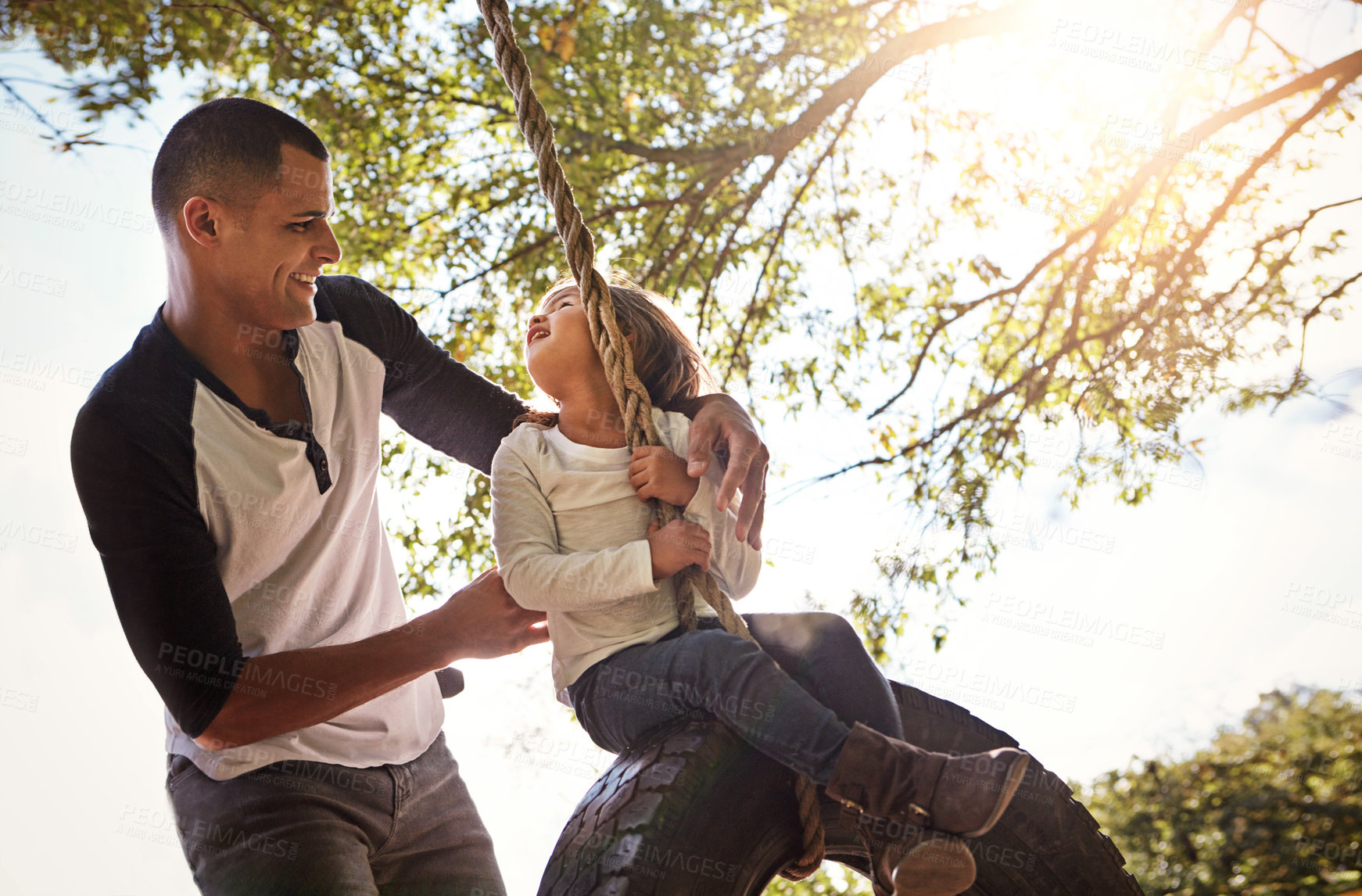 Buy stock photo Dad, bonding and child on tree swing, happy and laughing with daughter, outdoor or playing with girl. Park, man and fun with kid, family and game with smile in nature, love and together on break