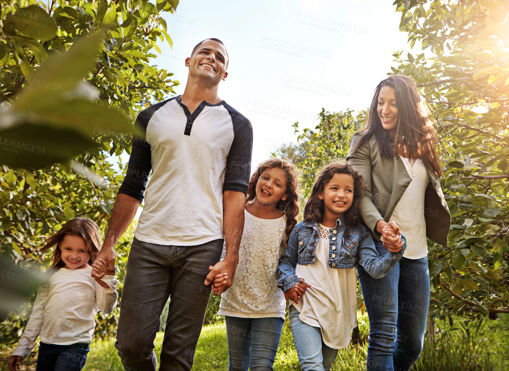 Buy stock photo Shot of a happy family of five going for a walk together through a garden