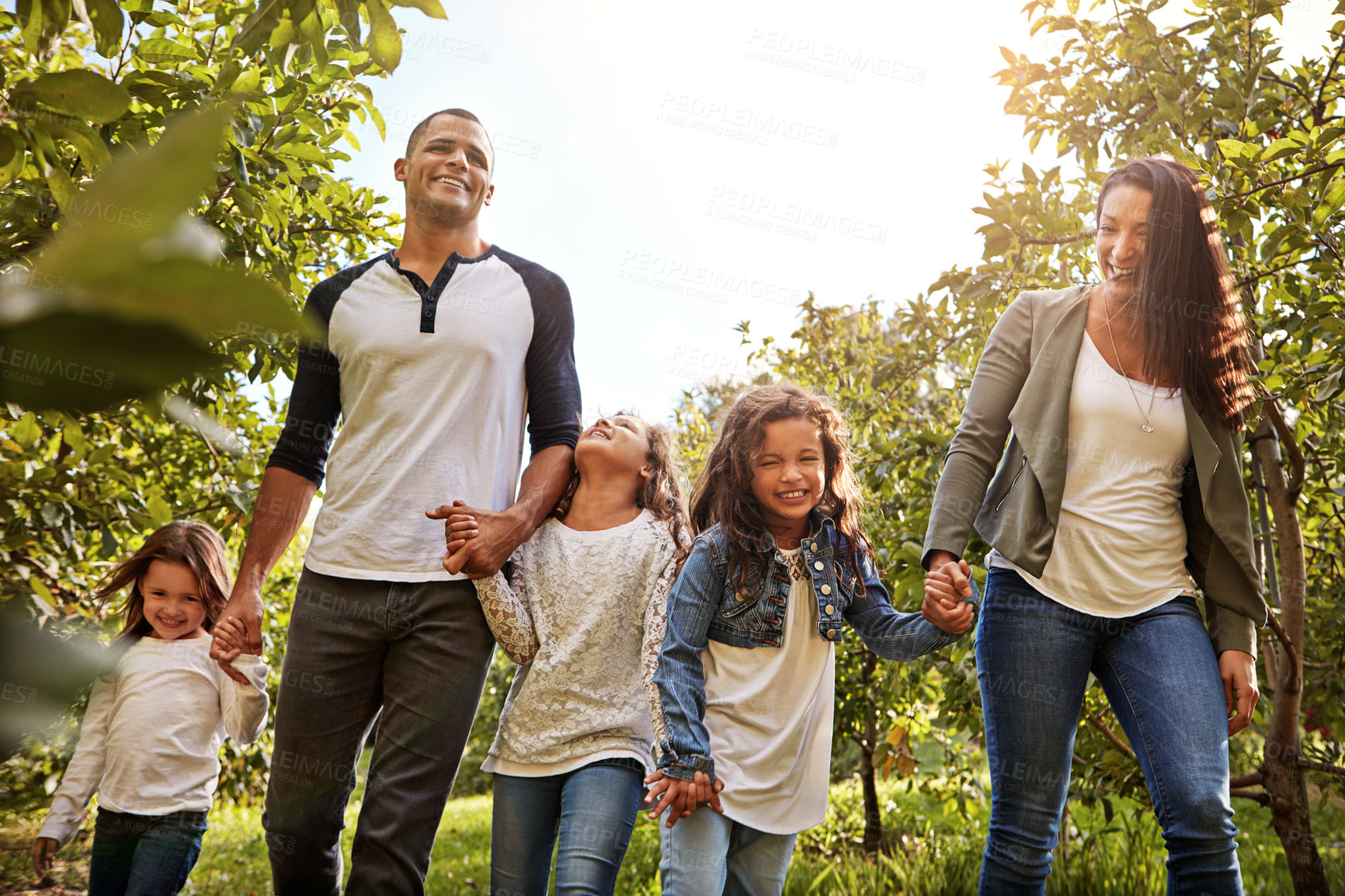 Buy stock photo Shot of a happy family of five going for a walk together through a garden