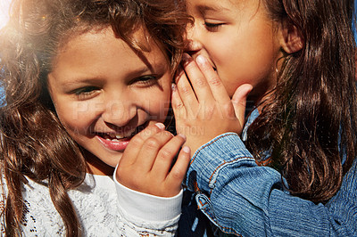 Buy stock photo Shot of a young girl whispering in her sister’s ear