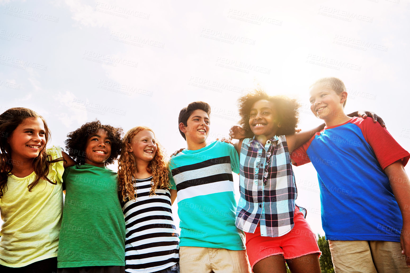 Buy stock photo Portrait of a group of diverse and happy kids hanging out together on a bright day outside