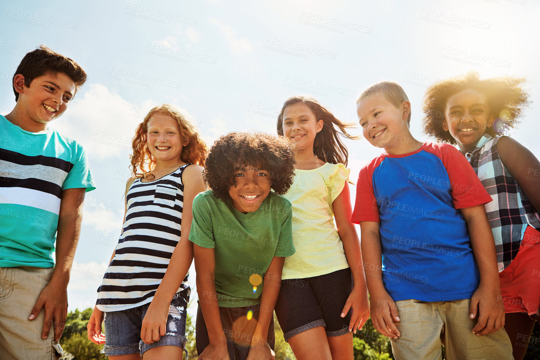 Buy stock photo Portrait of a group of diverse and happy kids hanging out together on a bright day outside