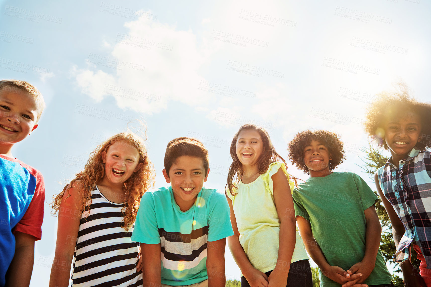 Buy stock photo Portrait of a group of diverse and happy kids hanging out together on a bright day outside