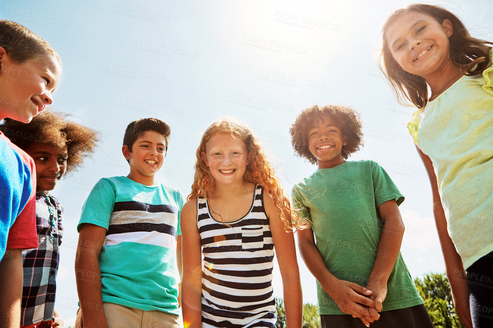 Buy stock photo Portrait of a group of diverse and happy kids hanging out together on a bright day outside