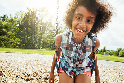 Buy stock photo Portrait of a young girl playing on a swing at the park