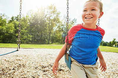 Buy stock photo Cropped shot of a young boy playing on a swing at the park