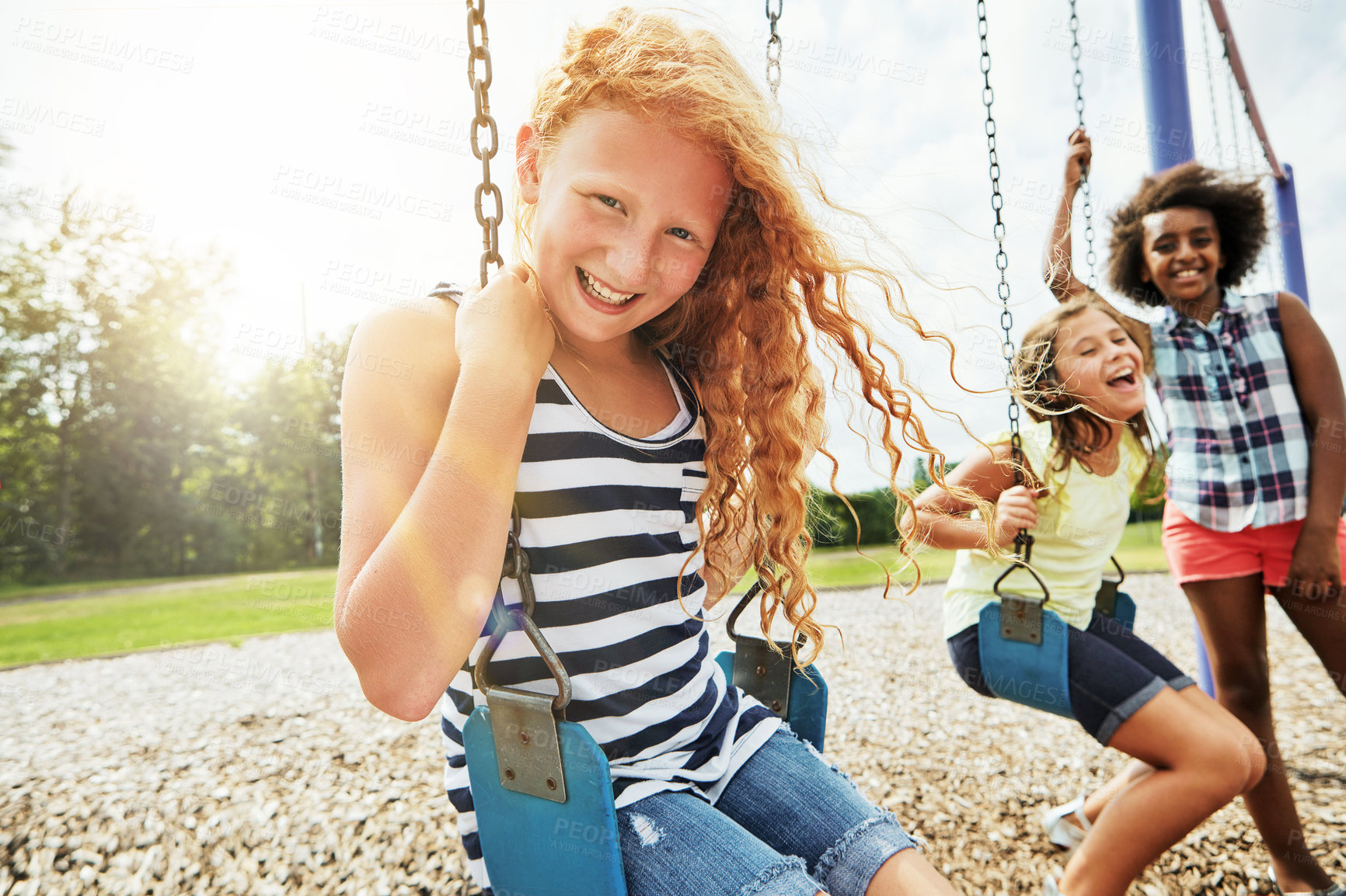 Buy stock photo Portrait of a young girl playing on a swing at the park with her friends