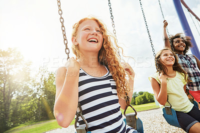 Buy stock photo Cropped shot of young girls playing on the swings at the park