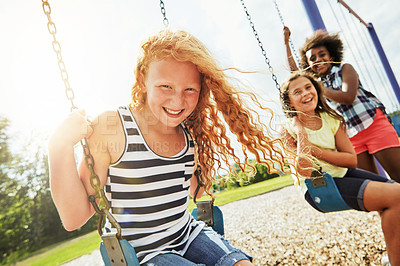 Buy stock photo Portrait of a young girl playing on a swing at the park with her friends